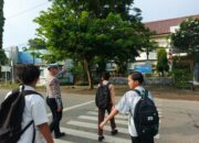 Personel Sat Lantas Polres Bima Kota Bantu Anak Sekolah Menyeberang Jalan